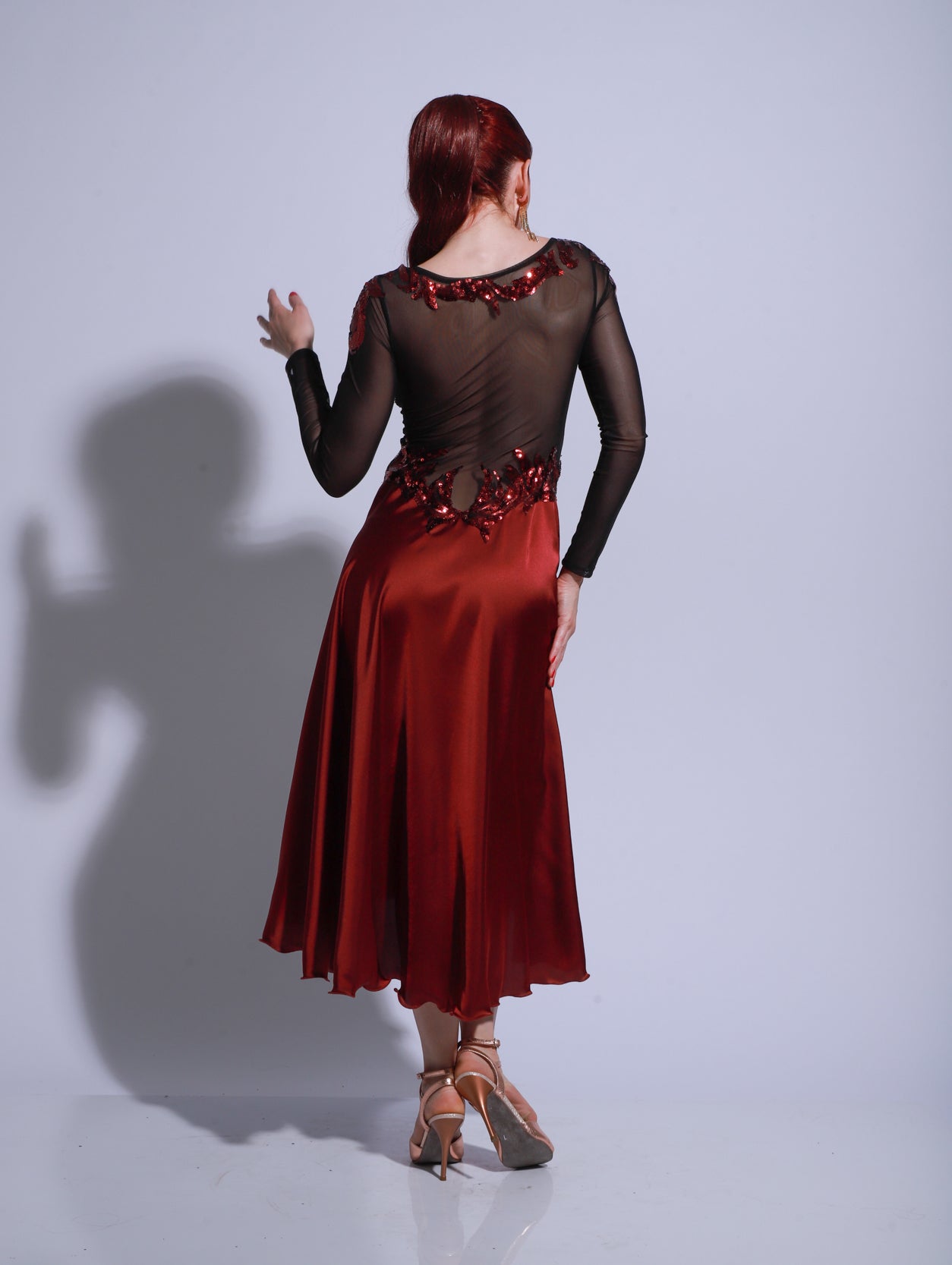 Vestido de escenario de tango en color rojo con cuerpo de encaje negro, mangas largas transparentes y falda con tajo y caída fluida.