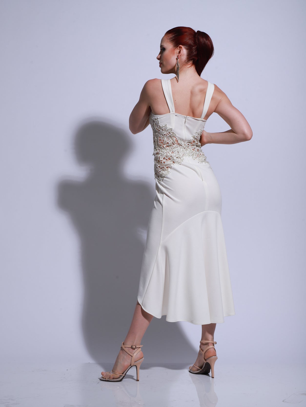 Vestido de tango blanco con cuerpo bordado, silueta entallada y tajo lateral, modelo posando con un brazo elevado