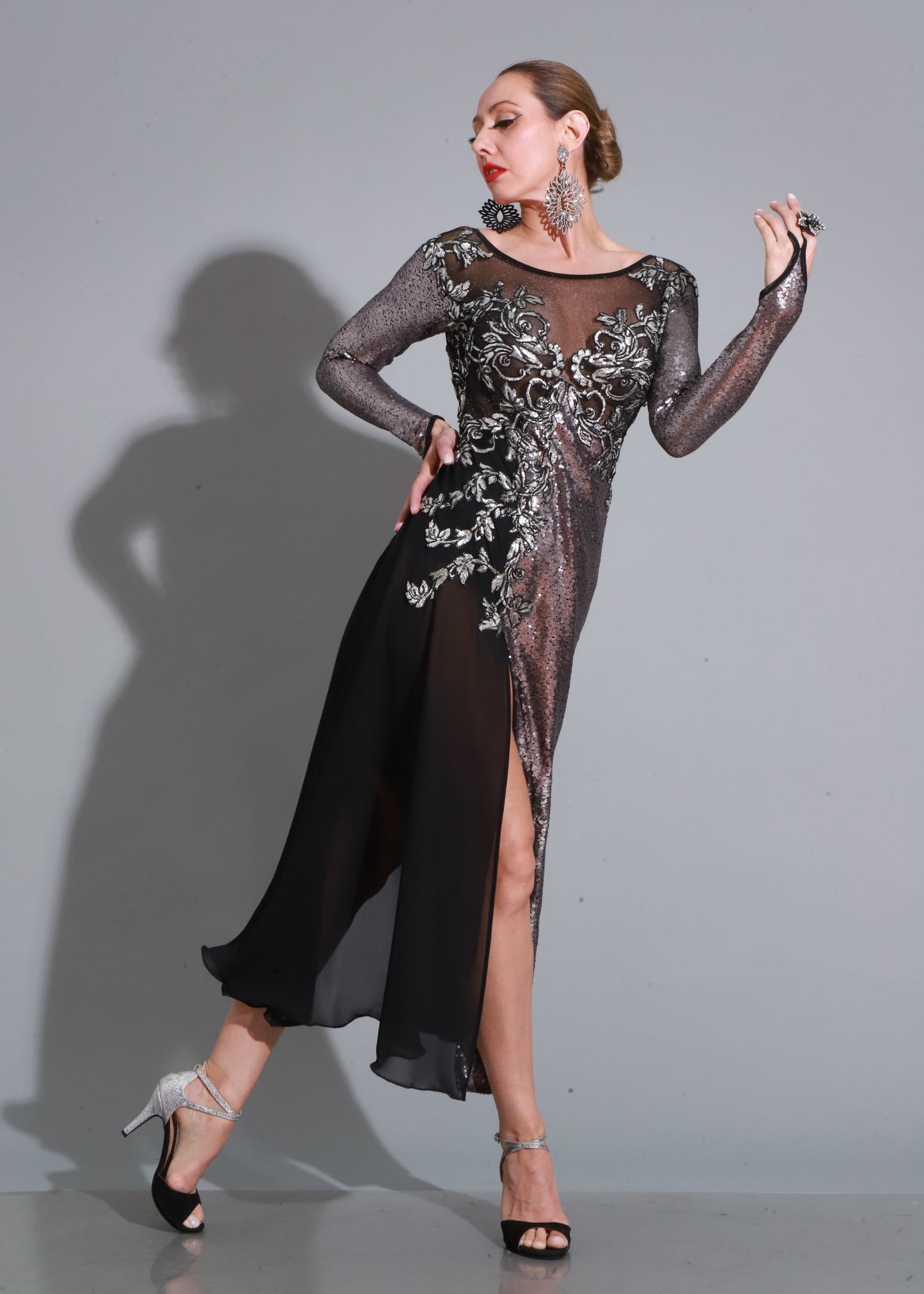Diseño con transparencias y bordados en plata sobre tul negro, falda con abertura y caída fluida para un look imponente y sensual.