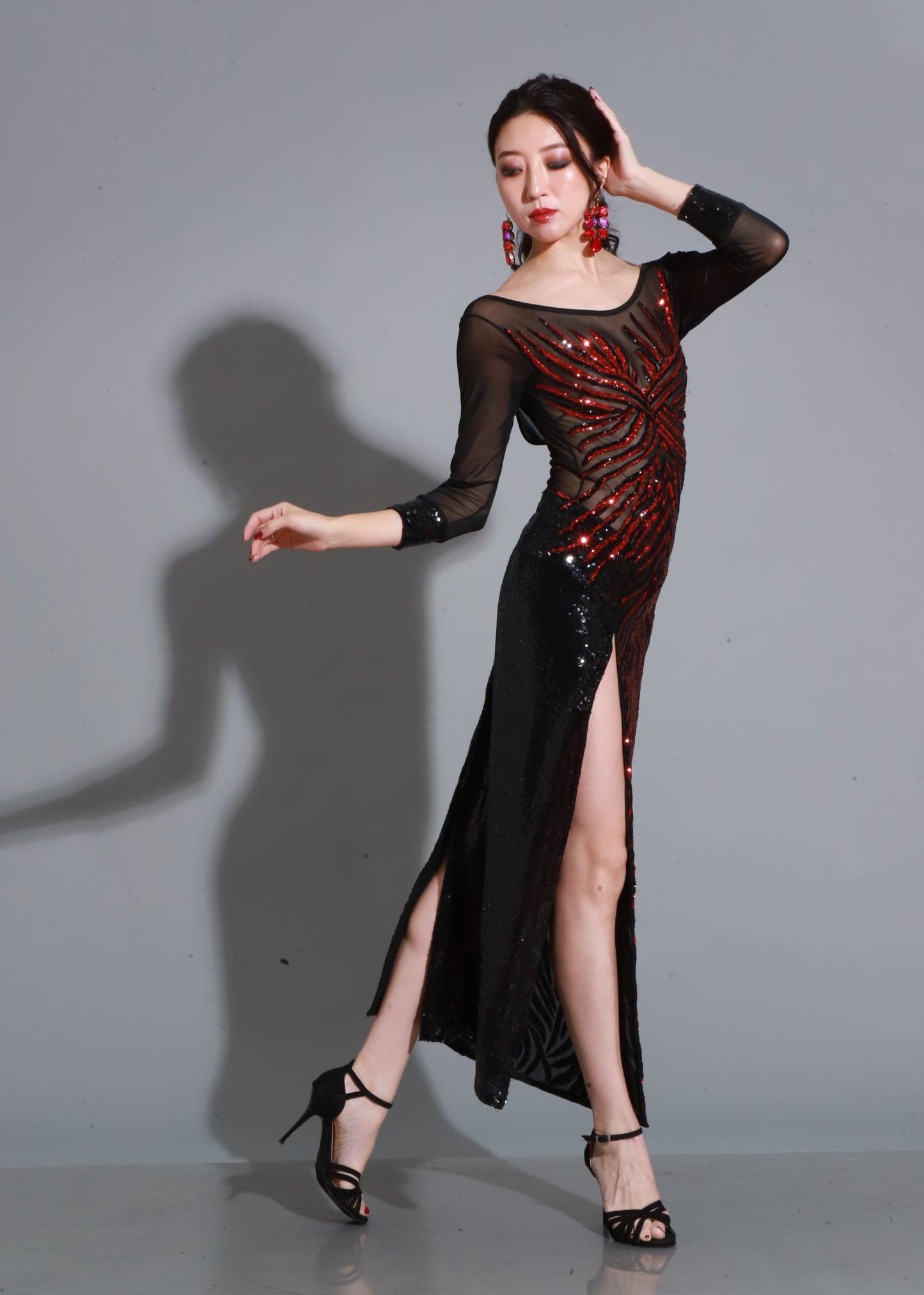 Elegante vestido de tango con cuerpo de tul y paillette en tonos rojo y negro, escote barco, mangas largas transparentes y abertura lateral que realza el movimiento al bailar.

