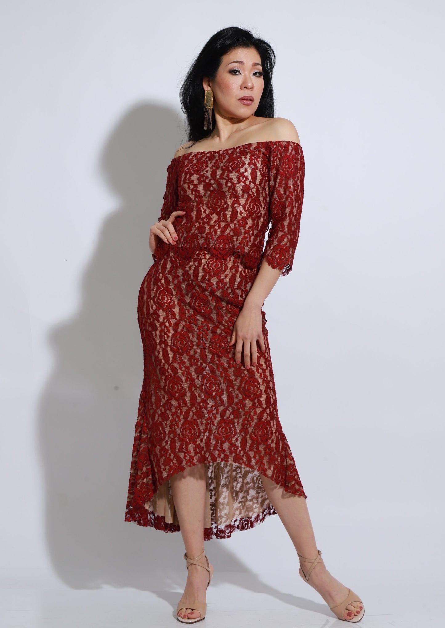 Elegante vestido de encaje en color rojo, diseñado con un delicado escote estilo hombros caídos y mangas tres cuartos. Su falda asimétrica aporta movimiento y una caída sofisticada, ideal para eventos especiales, tango o ocasiones donde se busque un look refinado y femenino. El encaje suave y la silueta entallada realzan la figura con un estilo romántico y moderno.